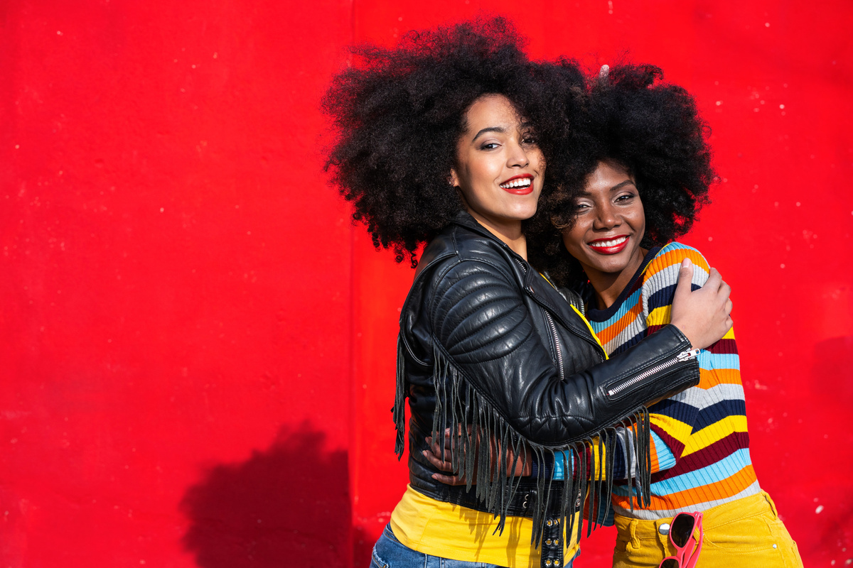 Cheerful afro women standing together and smiling on colorful backgraund
